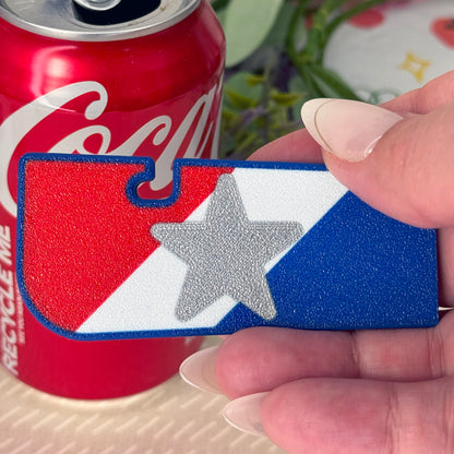 Hand holding a patriotic red, white and blue Tab Buddy XL with a Coca-Cola can in the background