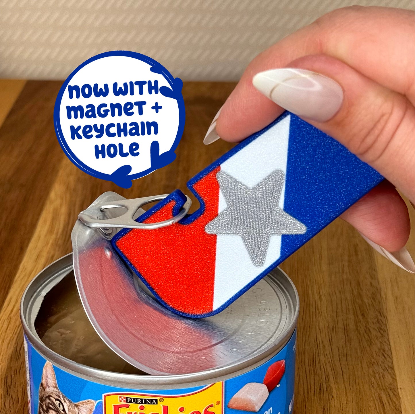 A patriotic USA-themed Tab Buddy XL opens a can of cat food. Text bubble states, "Now with magnet + keychain hole"