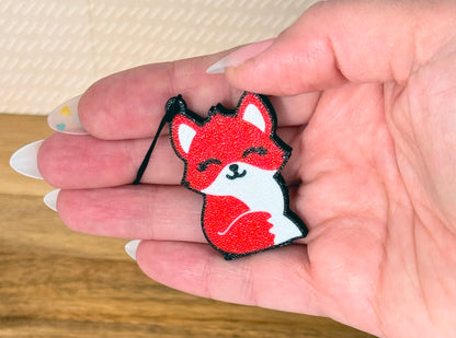 Hand holding a red fox-shaped Tab Buddy against a neutral background