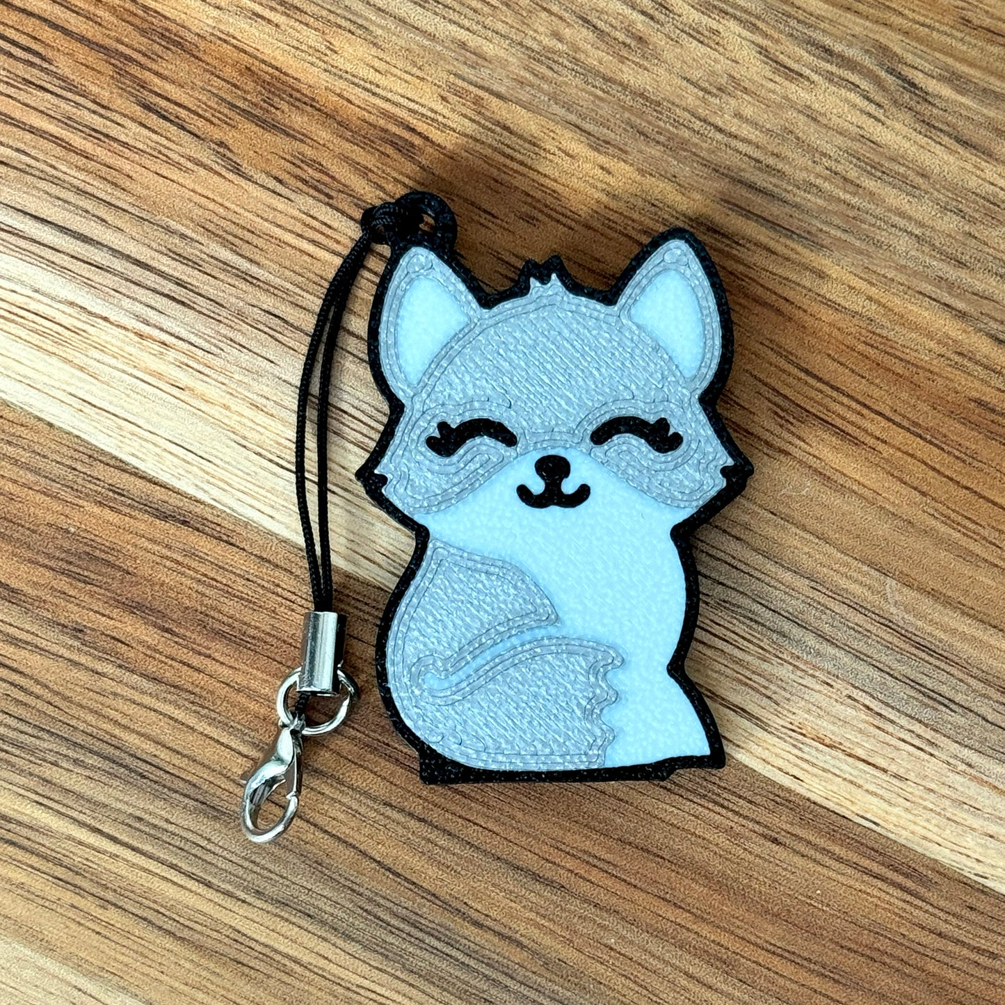 Tab Buddy Keychain with a cartoonish silver fox design on a wooden surface