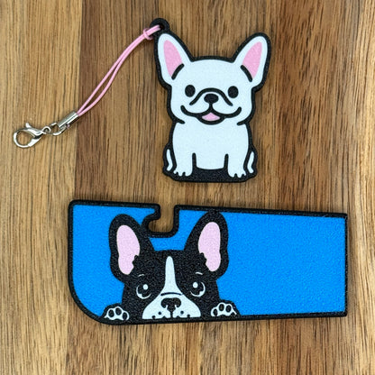 A set of French Bulldog-inspired soda Tab Buddy and Tab Buddy XL rest atop a wooden surface.