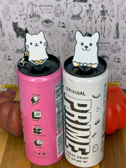 Two energy drink cans with ghost caat and ghost dog Tab Buddies on a wooden surface.