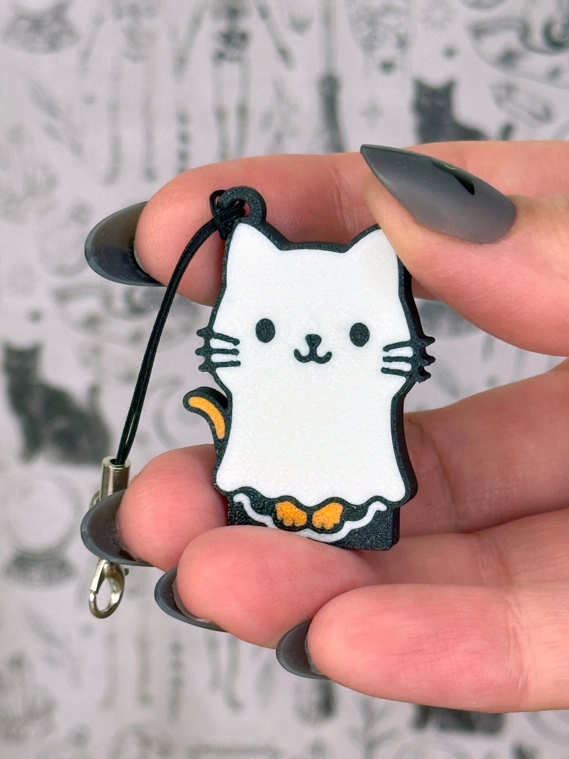 Hand holding a cat-shaped Tab Buddy keychain with a blurred snowy background