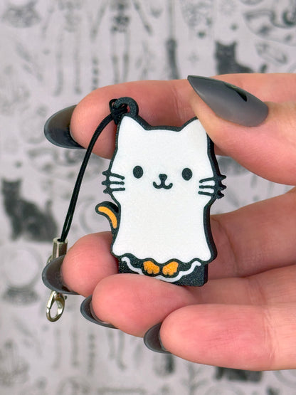 Hand holding a cat-shaped Tab Buddy keychain with a blurred snowy background