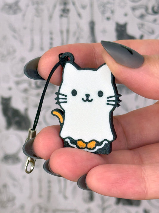 Hand holding a cat-shaped Tab Buddy keychain with a blurred snowy background