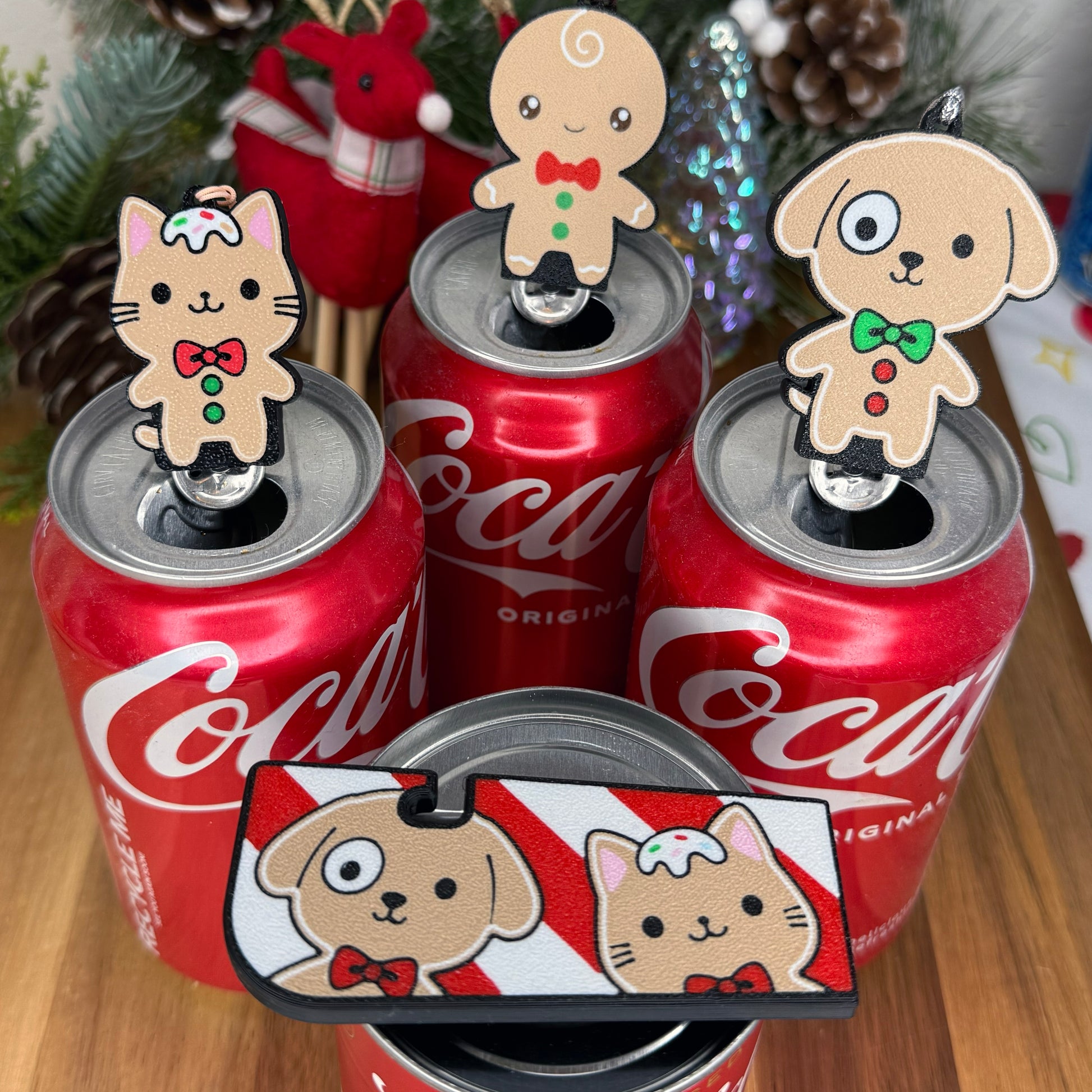 Cans with gingerbread themed Tab Buddies on a wooden surface.
