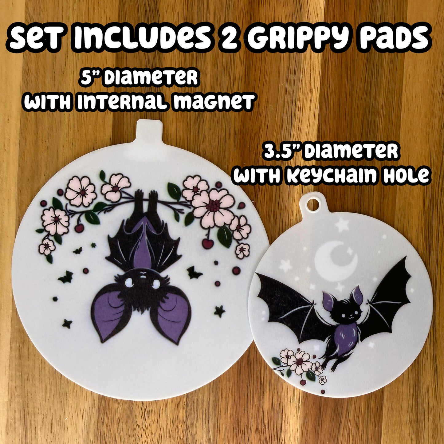Two bat-themed design circular grippy pads on a wooden background with text indicating set details -- The set includes 2 Grippy Pads: one 5" diameter with an internal magnet and one 3.5" diameter with a keychaini hole.