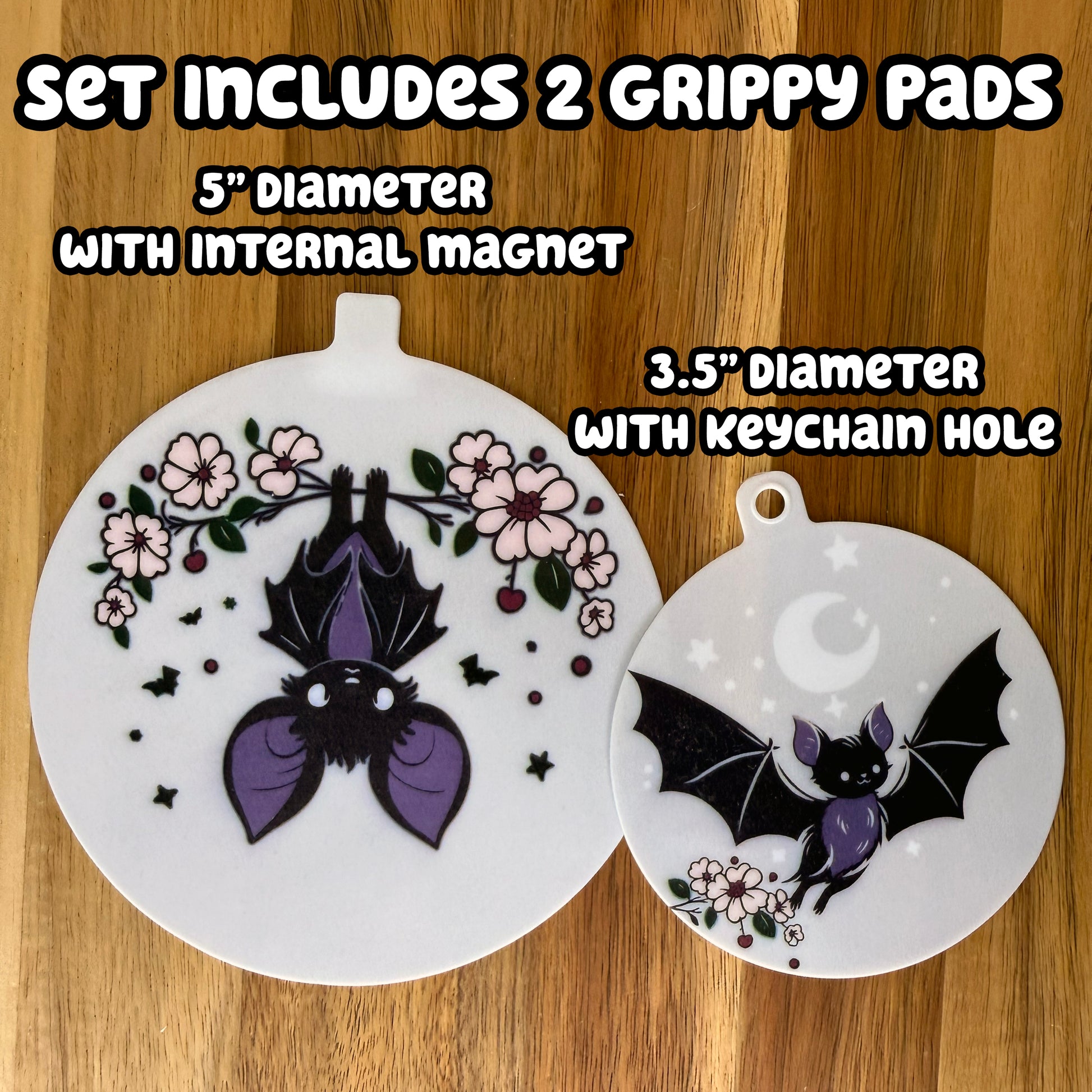 Two bat-themed design circular grippy pads on a wooden background with text indicating set details -- The set includes 2 Grippy Pads: one 5" diameter with an internal magnet and one 3.5" diameter with a keychaini hole.