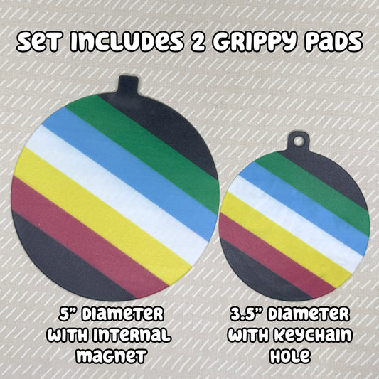 Two circular Disability Pride-themed Grippy Pads are shown atop a beige background. Text reads, "Set includes 2 Grippy Pads. 5" Diameter with internal magnet. 3.5" diameter with keychain hole."