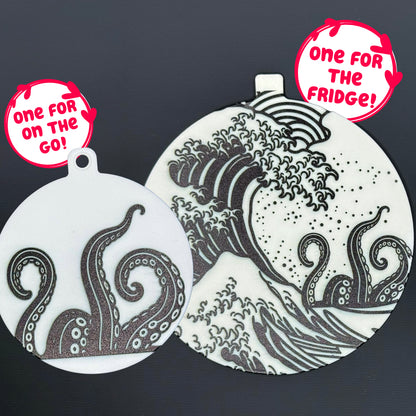 Two circular kraken-themed Grippy pads are shown against a grey background. Text bubbles read, "One for the fridge," and "One for on the go!"
