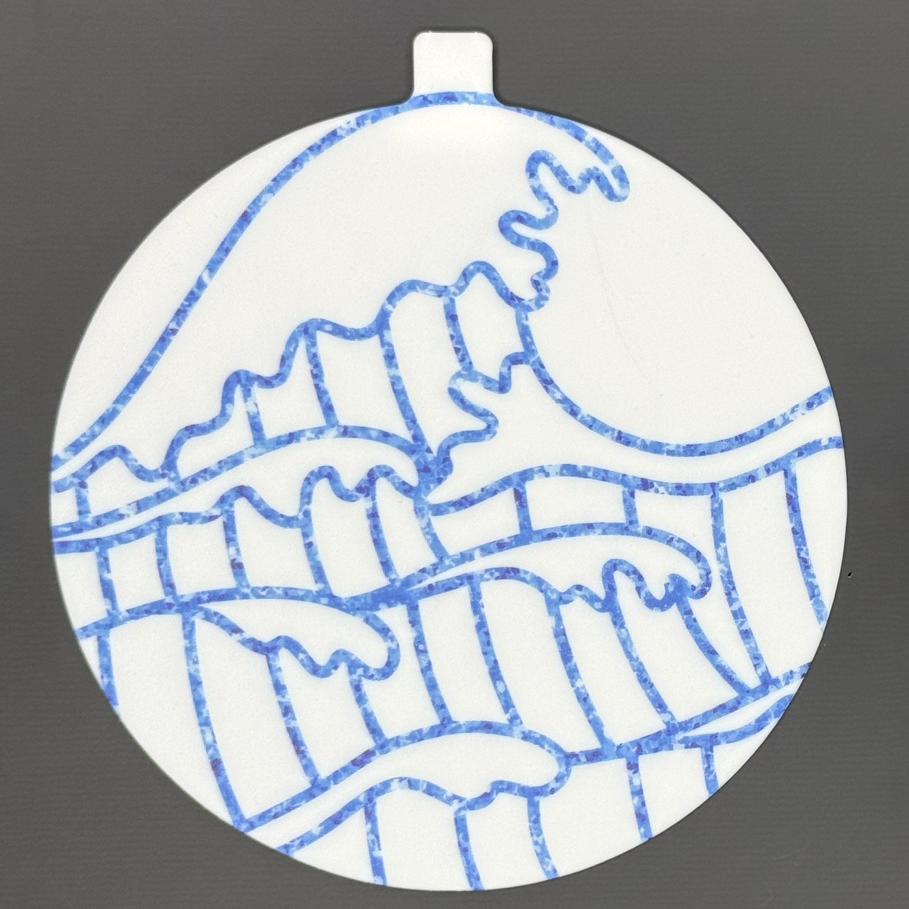 The large 5" diameter size Grippy Pad of the Sunny Shores set is shown against a grey background. The design  includes an internal magnet in a tab at the top and features sparkling blue waves crashing across the surface.