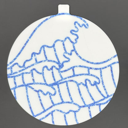 The large 5" diameter size Grippy Pad of the Sunny Shores set is shown against a grey background. The design  includes an internal magnet in a tab at the top and features sparkling blue waves crashing across the surface.