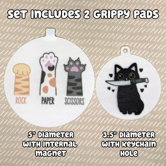 Two circular cat-themed Grippy Pads are shown atop a beige background. Text reads, "Set includes 2 Grippy Pads. 5" Diameter with internal magnet. 3.5" diameter with keychain hole."
