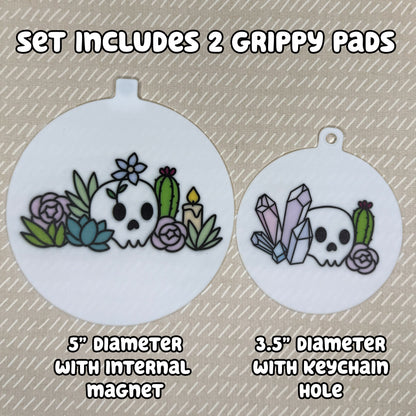 Two circular Mystic Garden-themed Grippy Pads are shown atop a beige background. Text reads, "Set includes 2 Grippy Pads. 5" Diameter with internal magnet. 3.5" diameter with keychain hole."