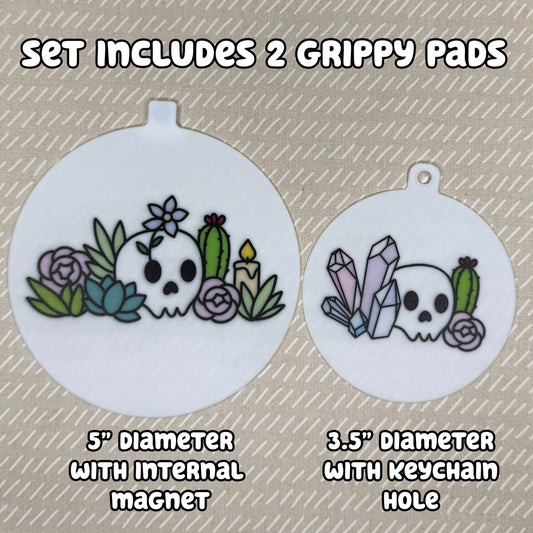 Two circular Mystic Garden-themed Grippy Pads are shown atop a beige background. Text reads, "Set includes 2 Grippy Pads. 5" Diameter with internal magnet. 3.5" diameter with keychain hole."