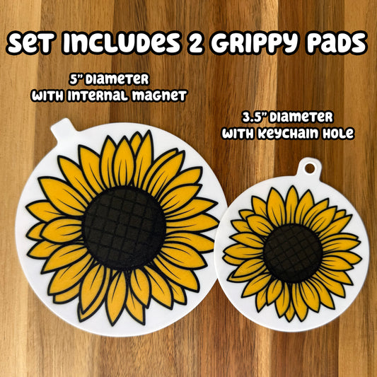Two circular sunflower-design grippy pads on a wooden background with text indicating set details -- The set includes 2 Grippy Pads: one 5" diameter with an internal magnet and one 3.5" diameter with a keychaini hole.