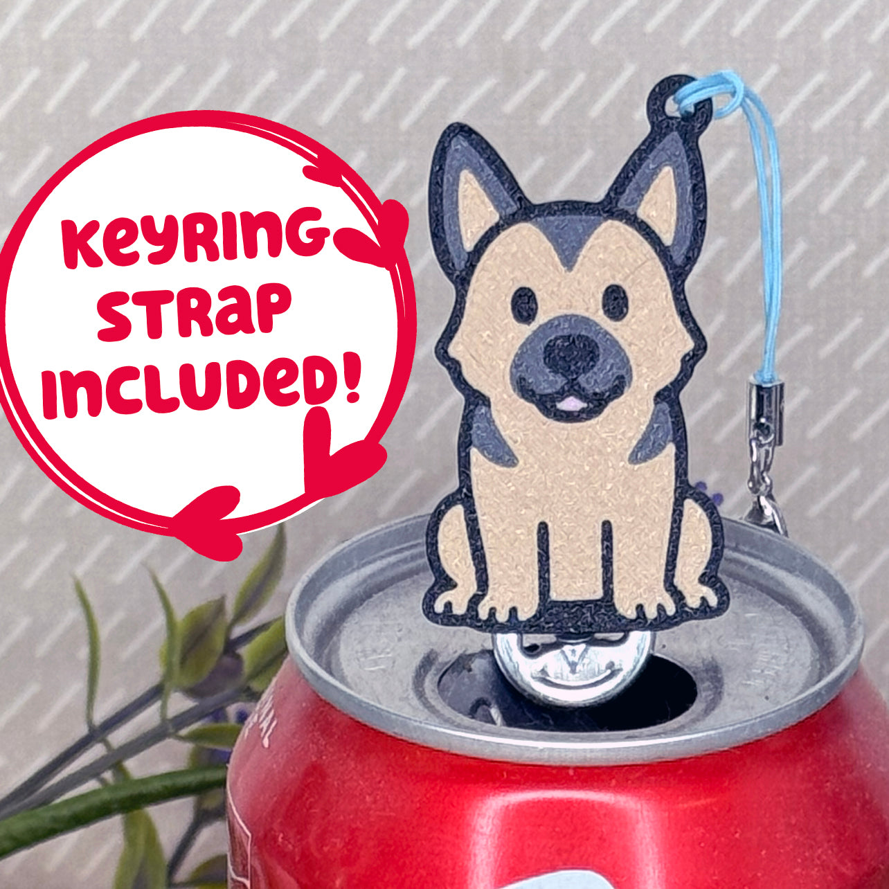 A tan and black German Shepherd-inspired Tab Buddy rests atop an open can tab. Desecriptive text reads "Keyring Strap Included!"