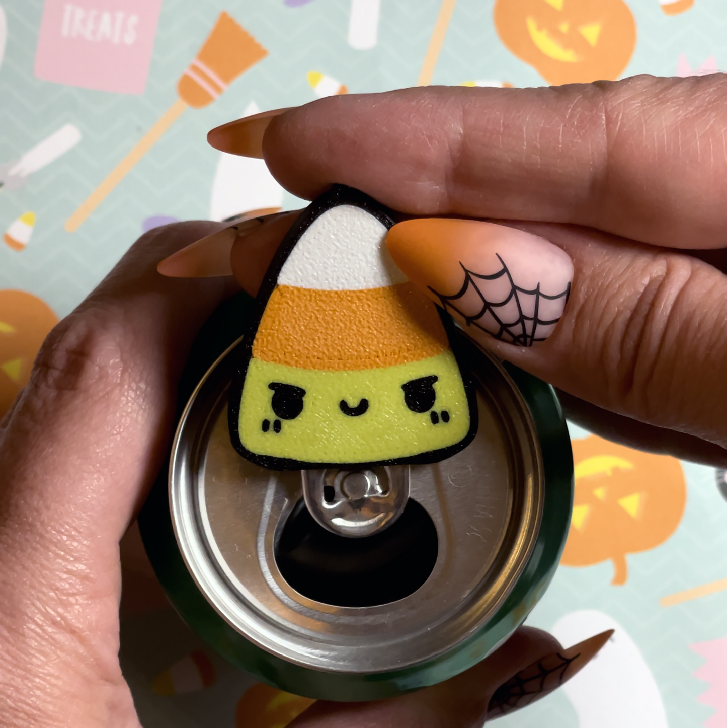 Hand holding a candy corn-shaped Tab Buddy with a Halloween-themed background