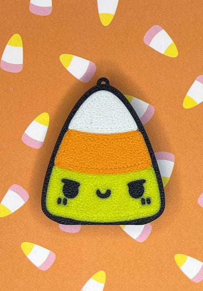 Candy corn-shaped Tab Buddy with a face on an orange background with candy corn patterns