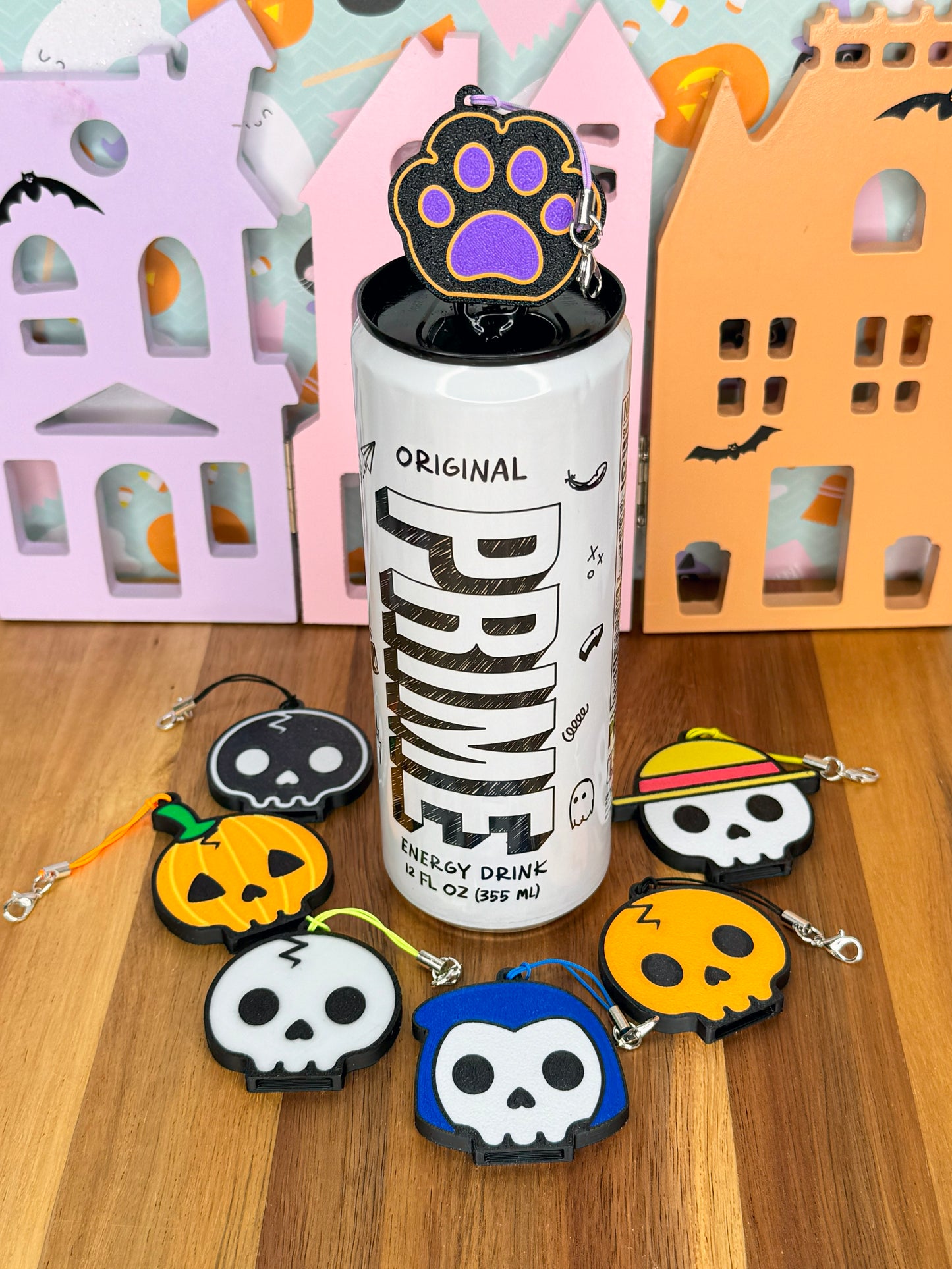 Can with halloween themed caw paw Tab Buddy on top, surrounded by colorful Tab Buddies on a wooden surface.