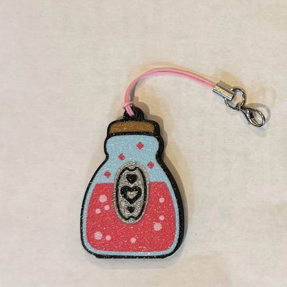 Pink love potion bottle Tab Buddy with keyring strap on a beige background