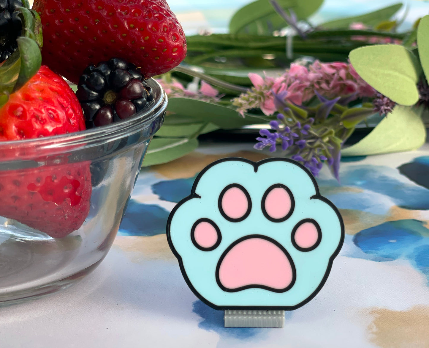 Cartoon cat paw Tab Buddy on a colorful background with strawberries and flowers