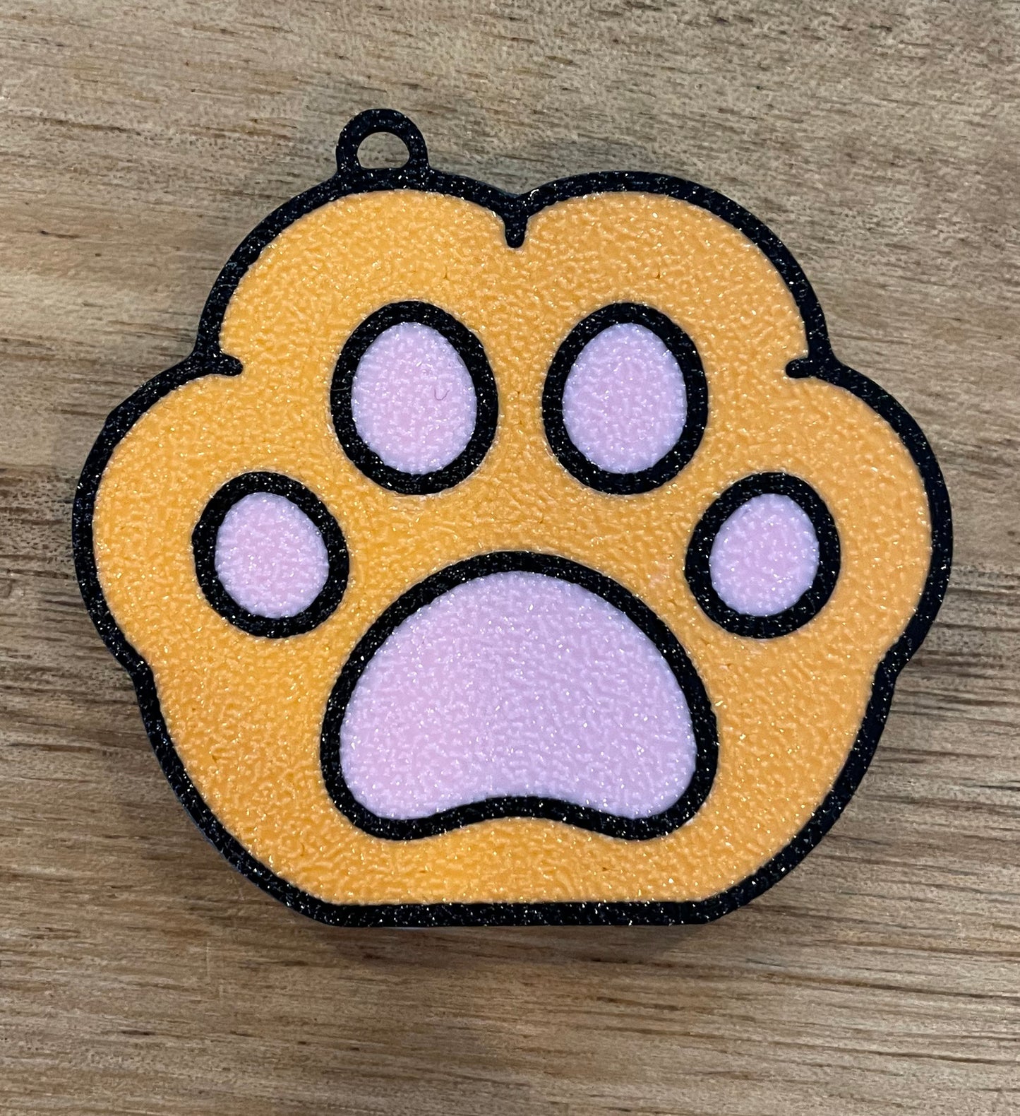 Orange paw print design Tab Buddy on a wooden surface