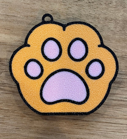 Orange paw print design Tab Buddy on a wooden surface