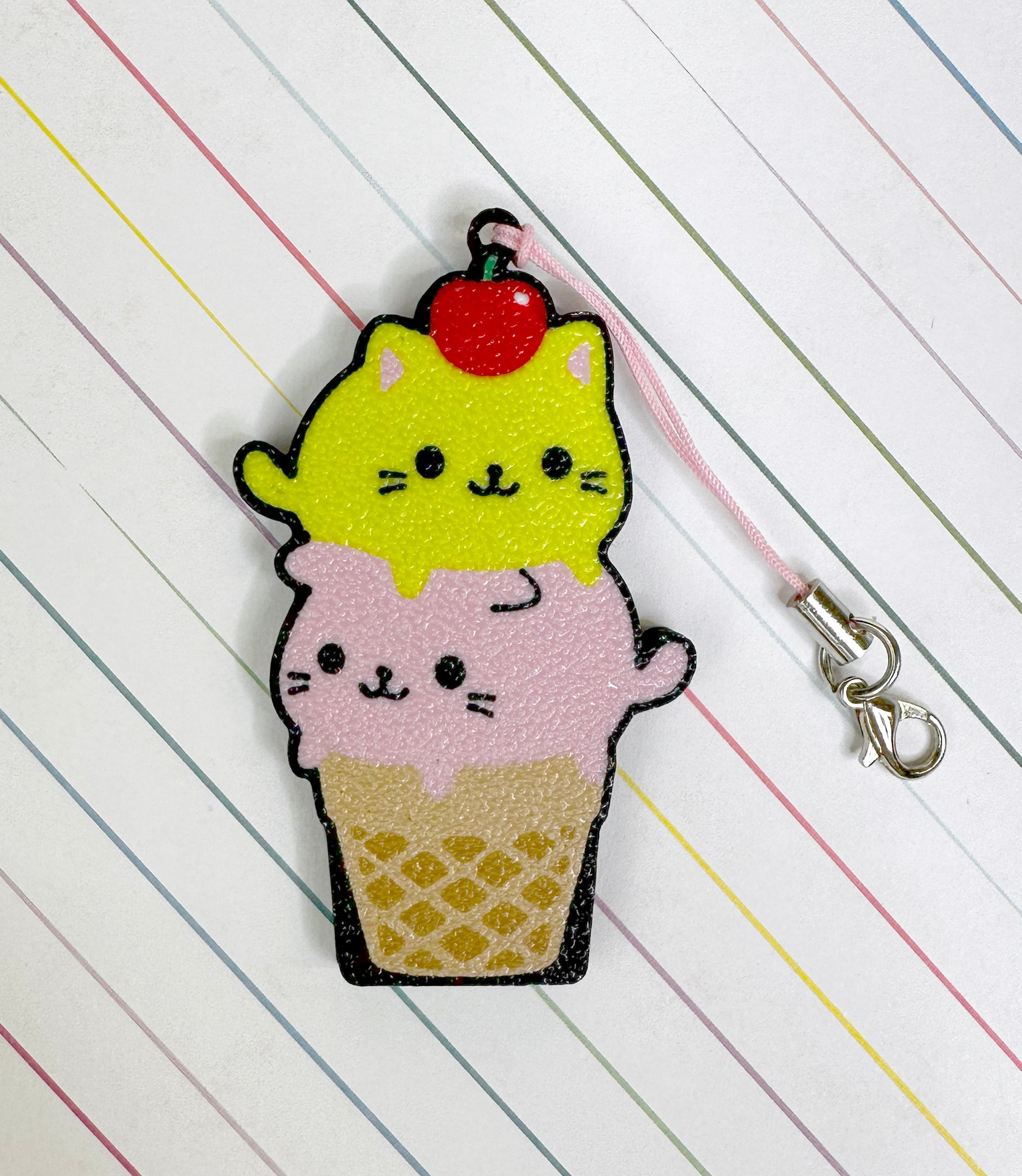 Cat-shaped ice cream cone Tab Buddy keychain on a striped background