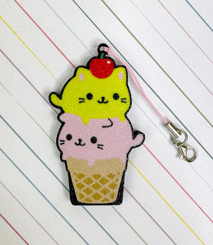 Cat-shaped ice cream cone Tab Buddy keychain on a striped background