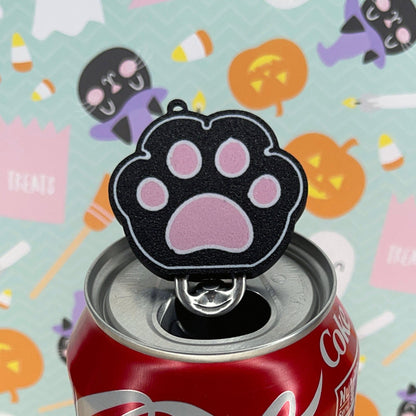 Coca-Cola can with a black paw print-shaped Tab Buddy on a Halloween-themed background