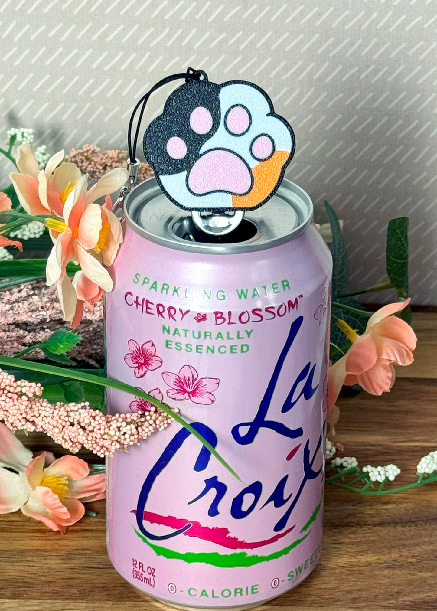 Sparkling water can with a paw-shaped Tab Buddy on a decorative background