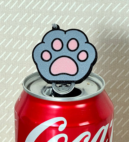 Coca-Cola can with a paw print-shaped Tab Buddy on a textured background