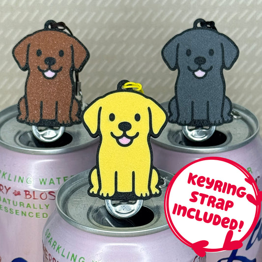 Labrador-inspired Soda Tab Buddies in yellow, chocolate and black rest atop the tabs of pink soda cans. Descriptive text reads "Keyring strap included!"