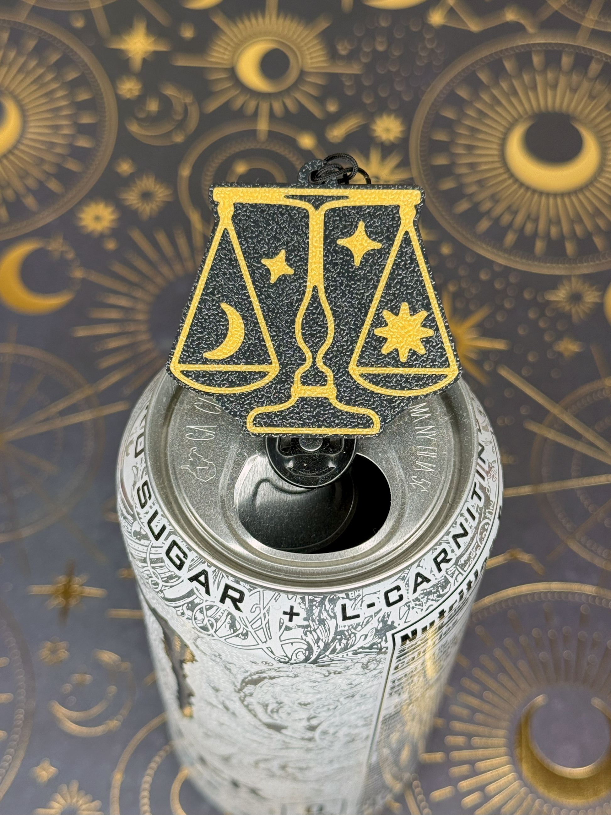 Can with a gold and black Libra zodiac Tab Buddy on a celestial pattern background