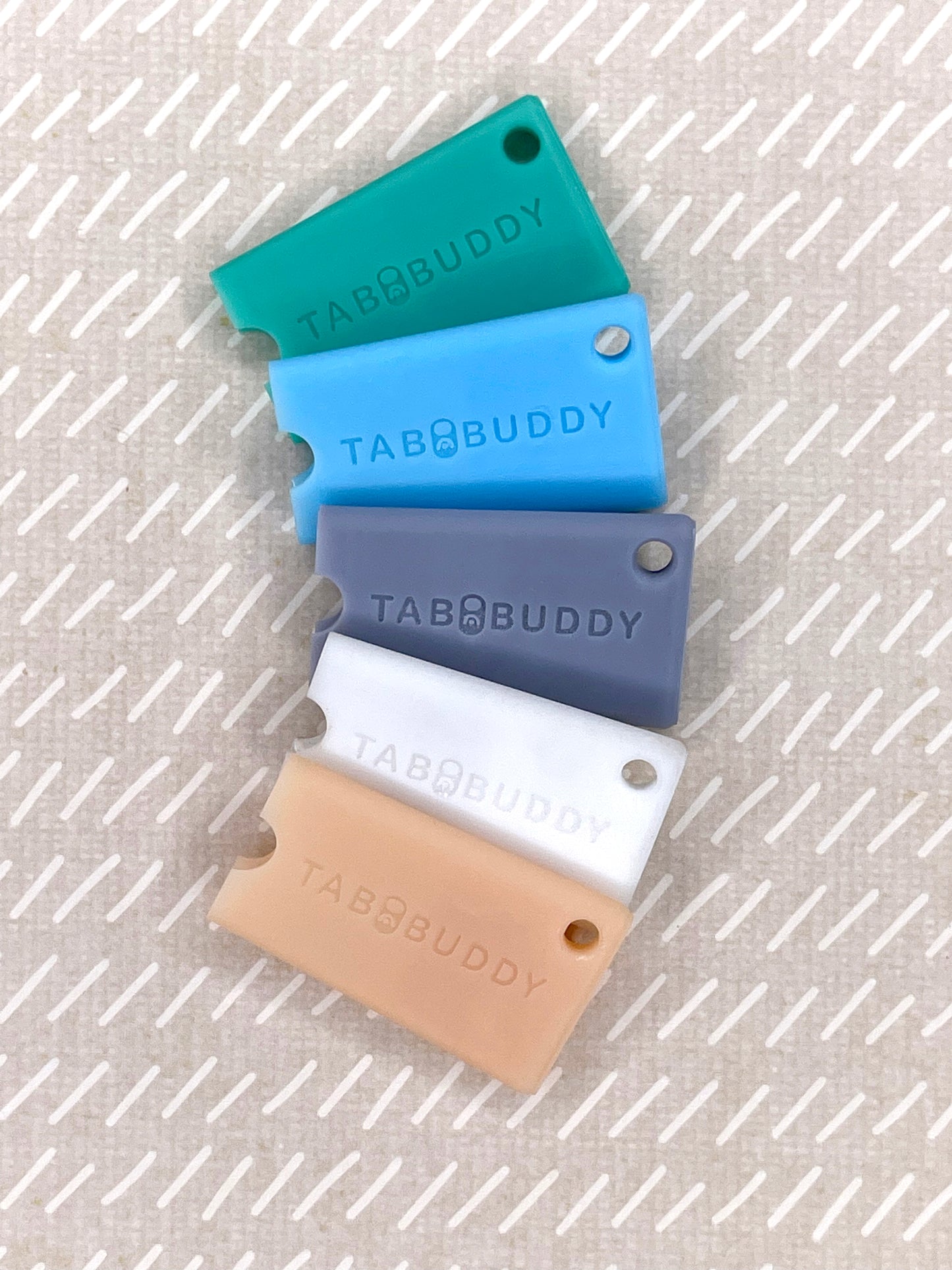 Set of five Tab Buddy Minis in different colors on a textured surface
