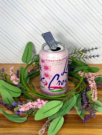 Pink can with translucent Onyx Tab Buddy Mini on a wooden surface with greenery and flowers