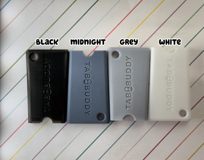 Four Tab Buddy Minis in black, midnight, grey, and white on a striped background.