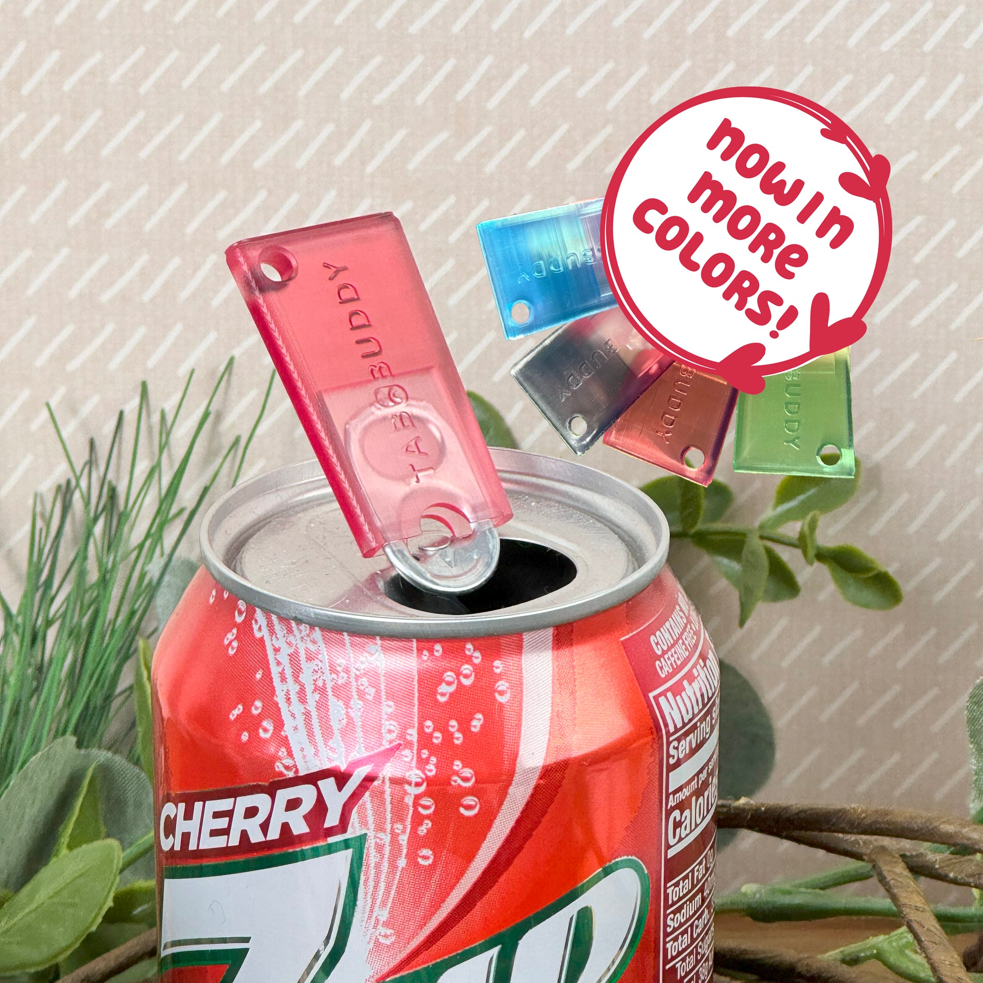 7UP cherry can with a Ruby red Tab Buddy Mini on a neutral background. Text bubbke reads "Now in more colors"