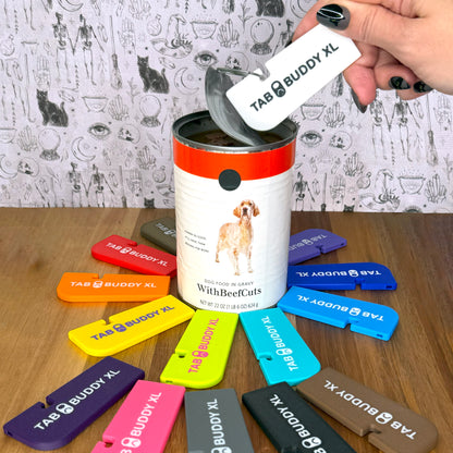 Collection of colorful 'Tab Buddy XL' products with a white one opening a can of pet food on a wooden surface.