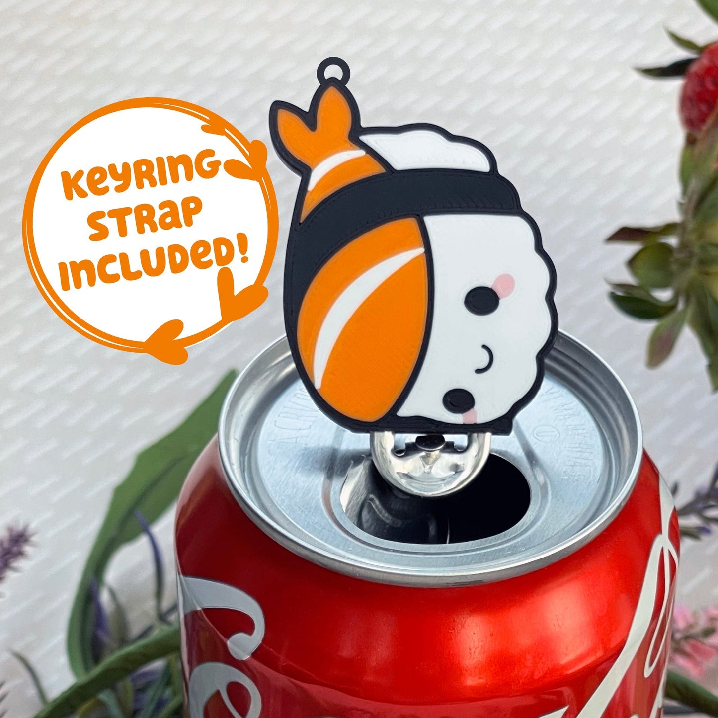 Coca-Cola can with a sushi themed Tab Buddy, surrounded by flowers and berries, with text that reads 'keyring strap included!'