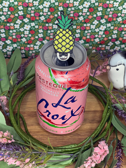 Pink sparkling water can with a pineapple-shaped Tab Buddy on a floral background