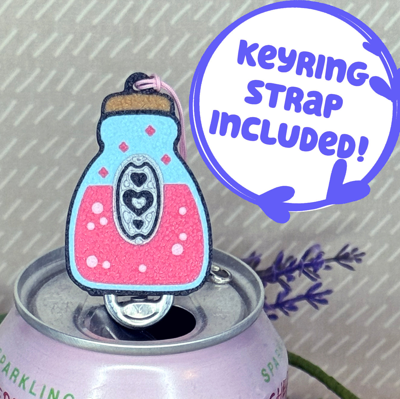Pink potion Tab Buddy rests atop a drink can. Descriptive text reads 'Keyring strap included!'.
