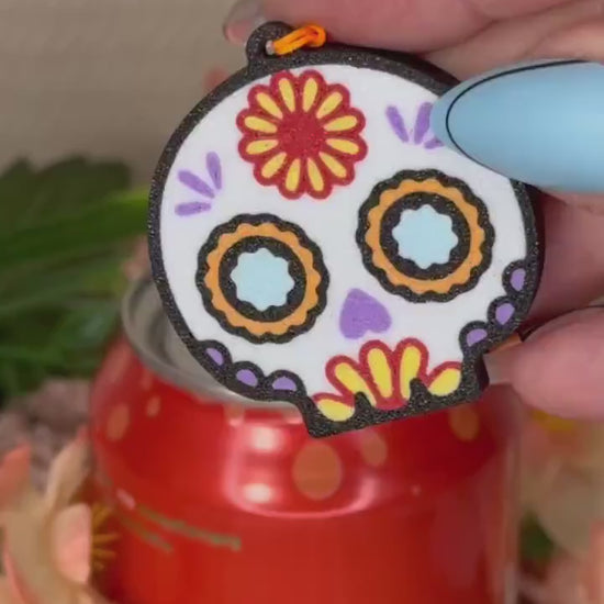 A Sugar Skull Tab Buddy opens a red can of Bubly. Subsequent images show other related skull designs of Tab Buddies.