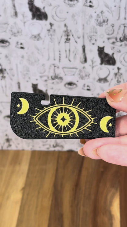 Two black and gold Tab Buddy XL designs are shown as complements to the Zodiac series of soda Tab Buddies. One then is shown opening a can of soup by lifting the tab and peeling back the lid while surrounded by the Zodiac Tab Buddies.