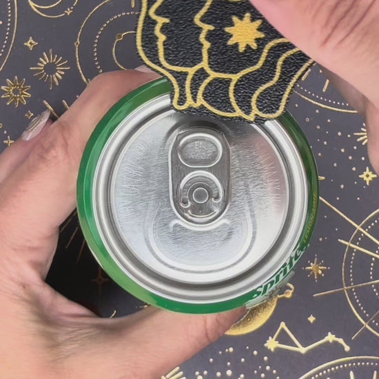a Gemini design black and gold  Tab Buddy is used to open a green can of Sprite sitting atop a celestial background. 12 total Zodiac designs are briefly shown.