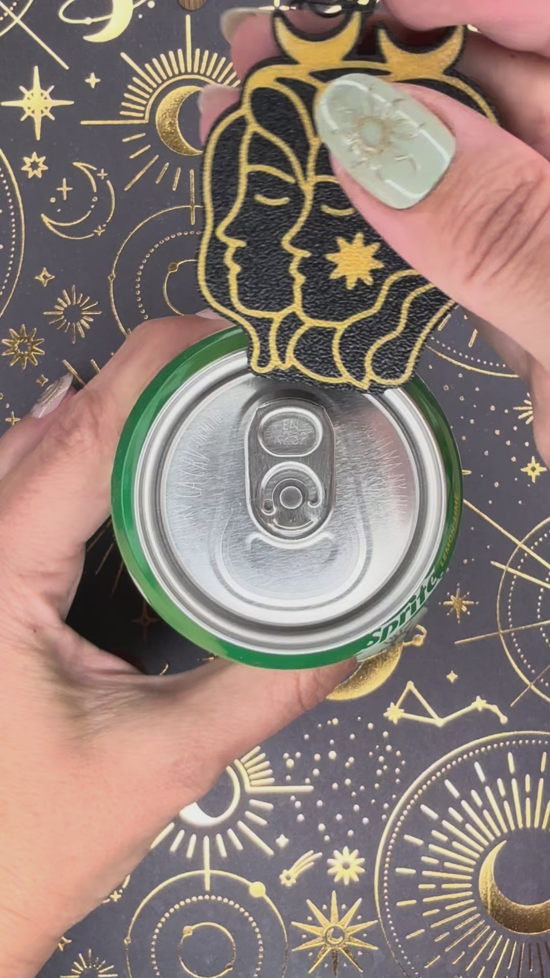 a Gemini design black and gold  Tab Buddy is used to open a green can of Sprite sitting atop a celestial background. 12 total Zodiac designs are briefly shown.