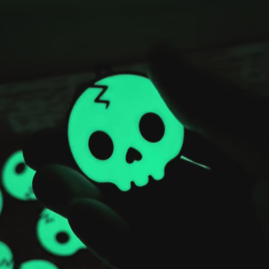 a glowing skull Tab Buddy is shown in the dark, then transitions to appearing green under regular light before opening a black Monster can. Other skull design Tab Buddies also are shown.