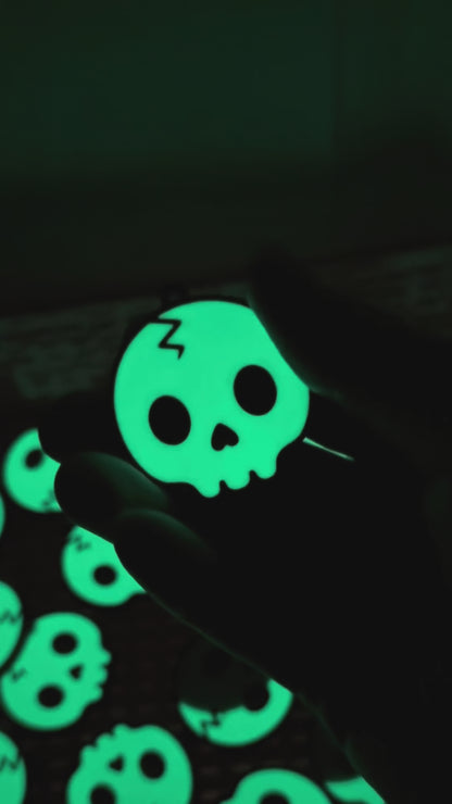 a glowing skull Tab Buddy is shown in the dark, then transitions to appearing green under regular light before opening a black Monster can. Other skull design Tab Buddies also are shown.