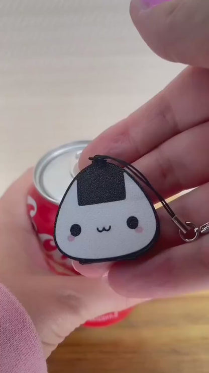 An onigiri rice ball-shaped Tab Buddy is used to open a red can of Coca-Cola.